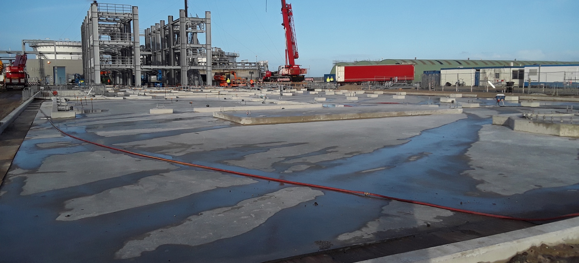 De betonnen fundatie van het Waste Water Treatment Project met op de achtergrond een heistelling